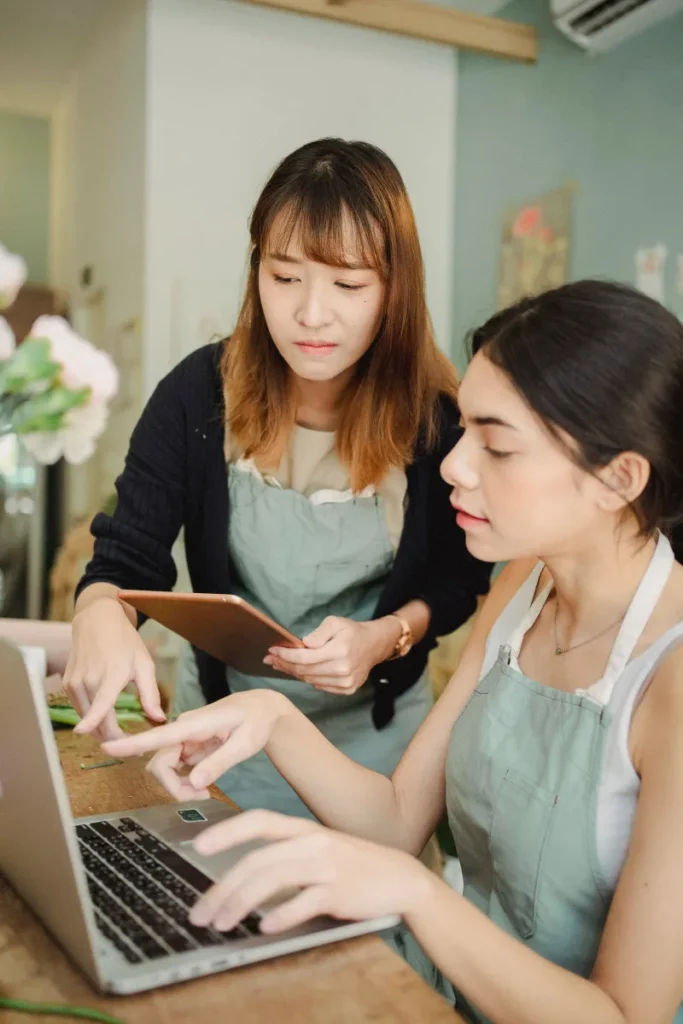 Hai chủ cửa hàng nhỏ kiểm tra đơn hàng online trên máy tính